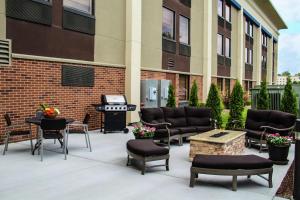 eine Terrasse mit Gartenmöbeln und einem Grill vor einem Gebäude in der Unterkunft Hampton Inn Joliet/I-80 in Joliet