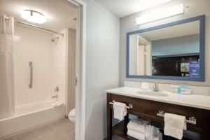 uma casa de banho com um lavatório, uma banheira e um espelho. em Hampton Inn Janesville em Janesville