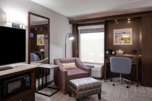 Habitación de hotel con TV, silla y escritorio. en Hampton Inn Janesville, en Janesville