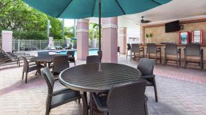 un patio con mesas, sillas y una sombrilla en DoubleTree by Hilton Sunrise - Sawgrass Mills, en Sunrise