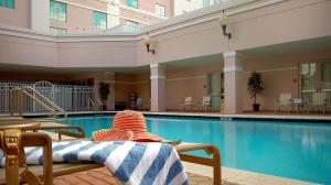 a hotel swimming pool with a person sitting on a chair next to it at DoubleTree by Hilton Sunrise - Sawgrass Mills in Sunrise