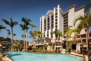 ein Hotel mit einem Pool und Palmen in der Unterkunft Embassy Suites by Hilton Fort Lauderdale 17th Street in Fort Lauderdale