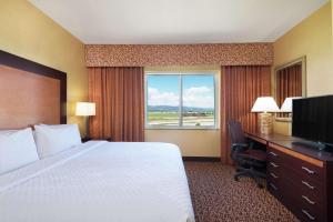 a hotel room with a bed and a desk and a window at Embassy Suites by Hilton Loveland Conference Center in Loveland