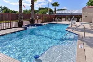 a swimming pool with blue water and palm trees at Hampton Inn Houston-Deer Park Ship Area in Deer Park