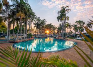 a large swimming pool with palm trees in a park at Broome Caravan Park in Broome