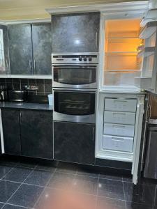 una cucina con elettrodomestici in acciaio inossidabile e armadietti neri di Krystal Residence a Londra