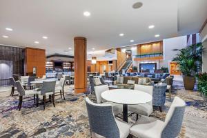 a lobby with tables and chairs and a restaurant at Embassy Suites by Hilton Houston-Energy Corridor in Houston