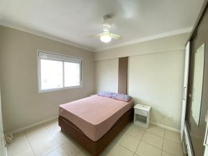 Schlafzimmer mit einem Bett und einem Fenster in der Unterkunft Apartamento capão da canoa in Capão da Canoa
