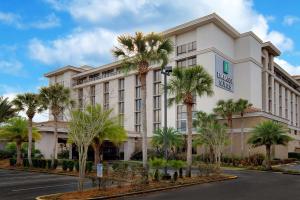 a hotel with palm trees in front of a street at Embassy Suites by Hilton Jacksonville Baymeadows in Jacksonville