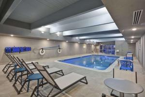 a large swimming pool with chairs and a table at Home2 Suites By Hilton Grand Rapids North in Grand Rapids