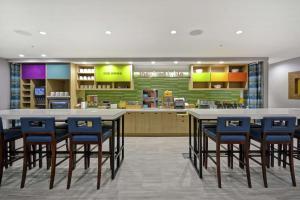 a large kitchen with blue chairs and a counter at Home2 Suites By Hilton Grand Rapids North in Grand Rapids