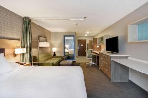 um quarto de hotel com uma cama e uma sala de estar em Home2 Suites By Hilton Grand Rapids North em Grand Rapids