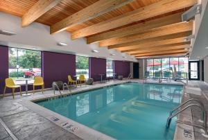 a swimming pool in a hotel with a table and chairs at Home2 Suites By Hilton Bordentown in Bordentown