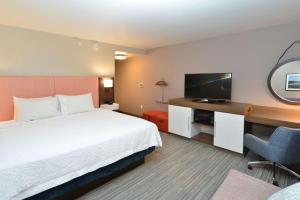 メノモニーにあるHampton Inn & Suites Menomonie-UW Stoutのベッド、デスク、テレビが備わるホテルルームです。