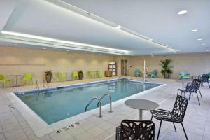 a pool in a hotel room with chairs and a table at Home2 Suites by Hilton Queensbury Lake George in Queensbury