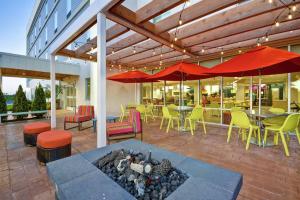 a patio with tables and chairs and red umbrellas at Home2 Suites by Hilton Queensbury Lake George in Queensbury