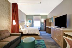 ein Hotelzimmer mit einem Bett und einem TV in der Unterkunft Home2 Suites by Hilton Queensbury Lake George in Queensbury
