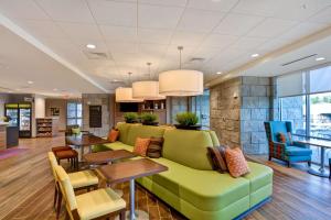 un vestíbulo con un sofá verde, mesas y sillas en Home2 Suites By Hilton Winston-Salem Hanes Mall en Winston-Salem