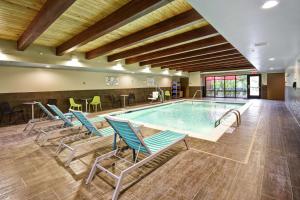 a swimming pool with chairs and a table in a building at Home2 Suites By Hilton Frankfort in Frankfort