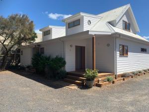une maison blanche avec une véranda et une allée. dans l'établissement Beach Park Phillip Island - Apartments, à Cowes