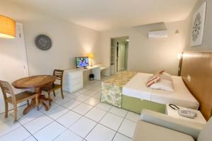 1 dormitorio con cama, escritorio y mesa en Búzios beach resort, en Búzios