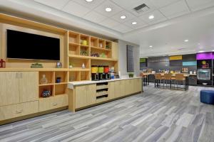 a waiting room with a flat screen tv and a restaurant at Home2 Suites By Hilton Springdale in Springdale