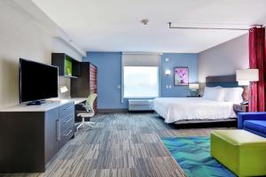 Home2 Suites By Hilton Springdale في سبرينغدل: غرفة فندقية بسرير وتلفزيون بشاشة مسطحة