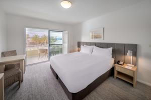 um quarto de hotel com uma cama e uma varanda em Oaks Port Stephens Pacific Blue Resort em Salamander Bay