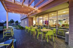 un patio avec des tables et des chaises dans un bâtiment dans l'établissement Home2 Suites By Hilton Terre Haute, à Terre Haute