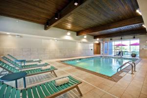 a pool with green lounge chairs and a swimming pool at Home2 Suites By Hilton Terre Haute in Terre Haute