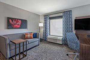 uma sala de estar com um sofá e uma televisão de ecrã plano em Hampton Inn & Suites Fort Wayne Downtown em Fort Wayne