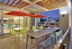 un patio con mesas, sillas y sombrillas rojas en Home2 Suites By Hilton Hagerstown, en Hagerstown