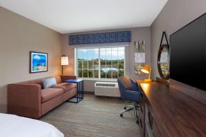 a hotel room with a couch and a television at Hampton Inn Cape Cod Canal in Buzzards Bay