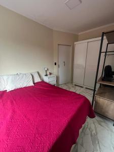 um quarto com uma cama grande e um cobertor vermelho em Apartamento em Ilha Porchat em São Vicente