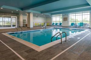 - une piscine dans le hall de l'hôtel avec des chaises bleues dans l'établissement Hilton Garden Inn By Hilton Fort Wayne North, à Sunnybrook Acres