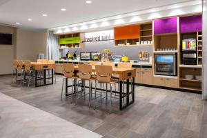 a restaurant with a bar with stools and a kitchen at Home2 Suites By Hilton Fort Wayne North in Sunnybrook Acres
