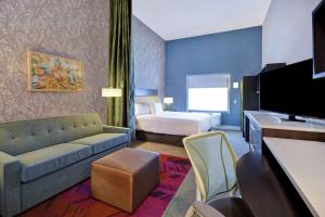 une chambre d'hôtel avec un canapé et un lit dans l'établissement Home2 Suites by Hilton Wichita Northeast, à Wichita