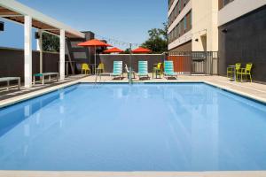 克洛维斯Home2 Suites By Hilton Clovis Fresno Airport的配有椅子和遮阳伞的大型游泳池