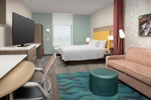克洛维斯Home2 Suites By Hilton Clovis Fresno Airport的配有床和沙发的酒店房间