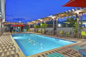 una piscina por la noche con sillas y mesas en Home2 Suites By Hilton Jacksonville South St Johns Town Ctr en Jacksonville