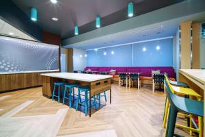 un restaurante con mesa, sillas y sofá púrpura en Tru By Hilton Goodyear Phoenix West, Az, en Goodyear