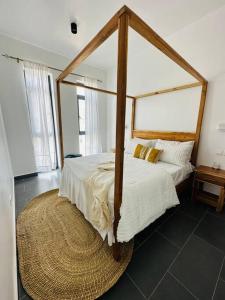 a bedroom with a bed with a four post canopy at Island style 2-bedroom apartment with pool "Ilava Boma" in Paje