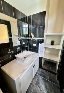 baño con lavabo blanco y azulejos negros en Cabaña La Betica, en Villavicencio