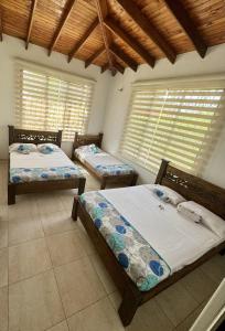 2 Betten in einem Zimmer mit 2 Fenstern in der Unterkunft Cabaña La Betica in Villavicencio