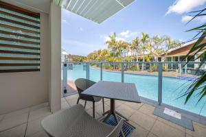 um pátio com uma mesa e cadeiras e uma piscina em Oaks Port Stephens Pacific Blue Resort em Salamander Bay