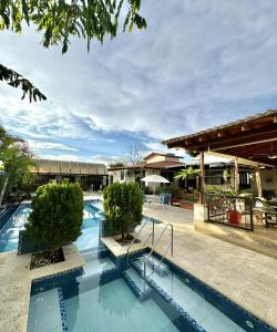 a swimming pool with two trees and a building at Cabaña La Betica in Villavicencio