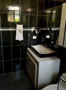 y baño con lavabo, aseo y espejo. en Cabaña La Betica, en Villavicencio