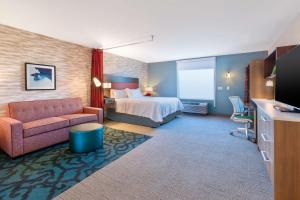 ein Hotelzimmer mit einem Bett und einem Sofa in der Unterkunft Home2 Suites By Hilton Saginaw, Mi in Saginaw