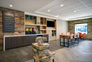 a waiting room with a bar and a table and chairs at Home2 Suites By Hilton Columbus in Columbus
