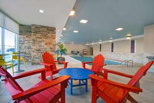 a swimming pool with red chairs and a blue table at Home2 Suites By Hilton Columbus in Columbus